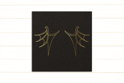 Line drawing of dragon wings on gold foil on black paper.