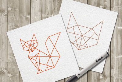 Orange geometric fox line drawing and brown geometric fox face line drawing. Both are on square white cards against a wood background. Black A Cricut brand pen is laying on top.