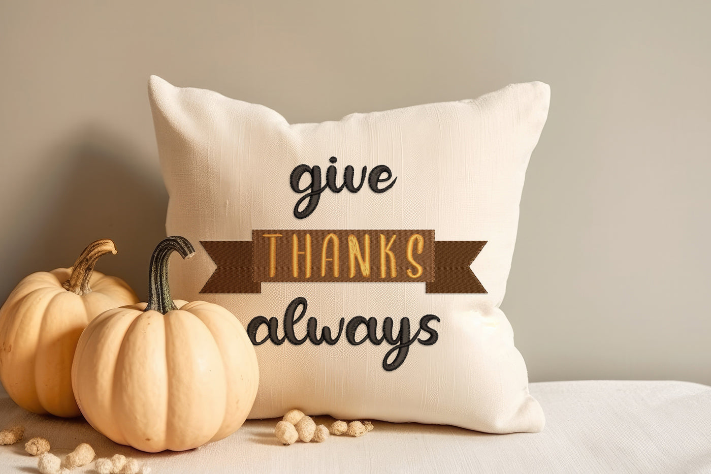 Decorative pillow with embroidered 'give thanks always' text and pumpkins on a neutral background