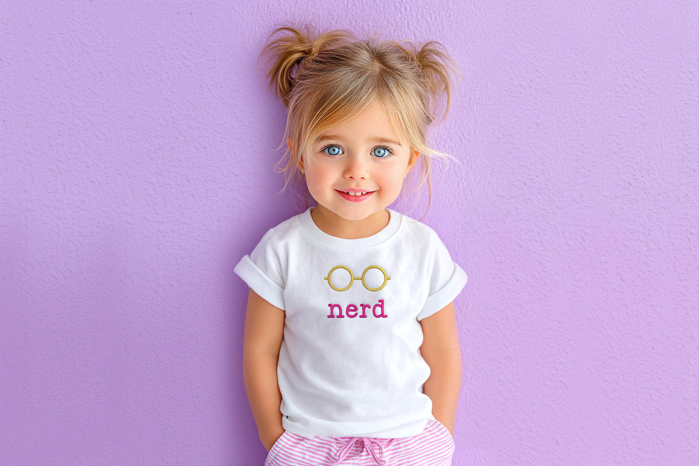 Child wearing a white t-shirt with 'nerd' and glasses embroidery