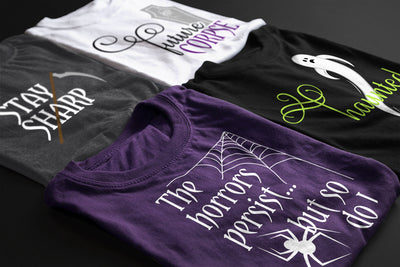 Four t-shirts with Halloween-themed designs on a dark surface