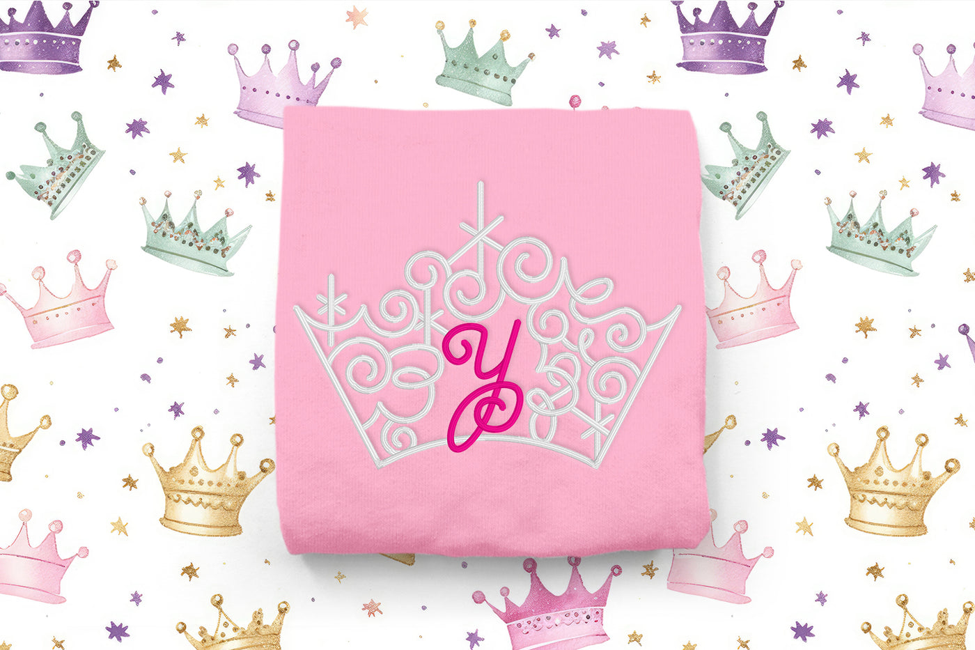 Pink shirt with a white tiara design and pink letter 'Y' on a background of colorful crowns and stars.