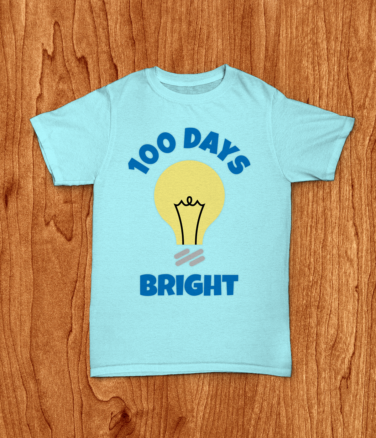 Light blue shirt on wood background. Shirt has a light bulb design with the words "100 days bright" around it.