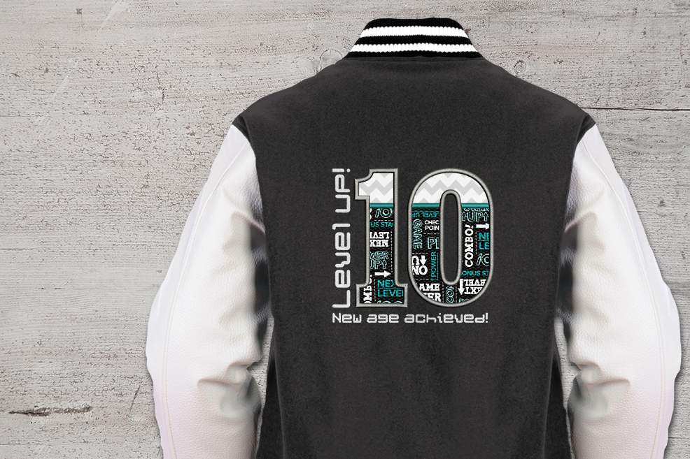 Letterman jacket with an applique 10. Around the 10 are embroidered the words "Level UP! New age achieved!"