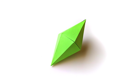 A 12-sided 3 dimensional gem made out of bright green paper sits on a white background.