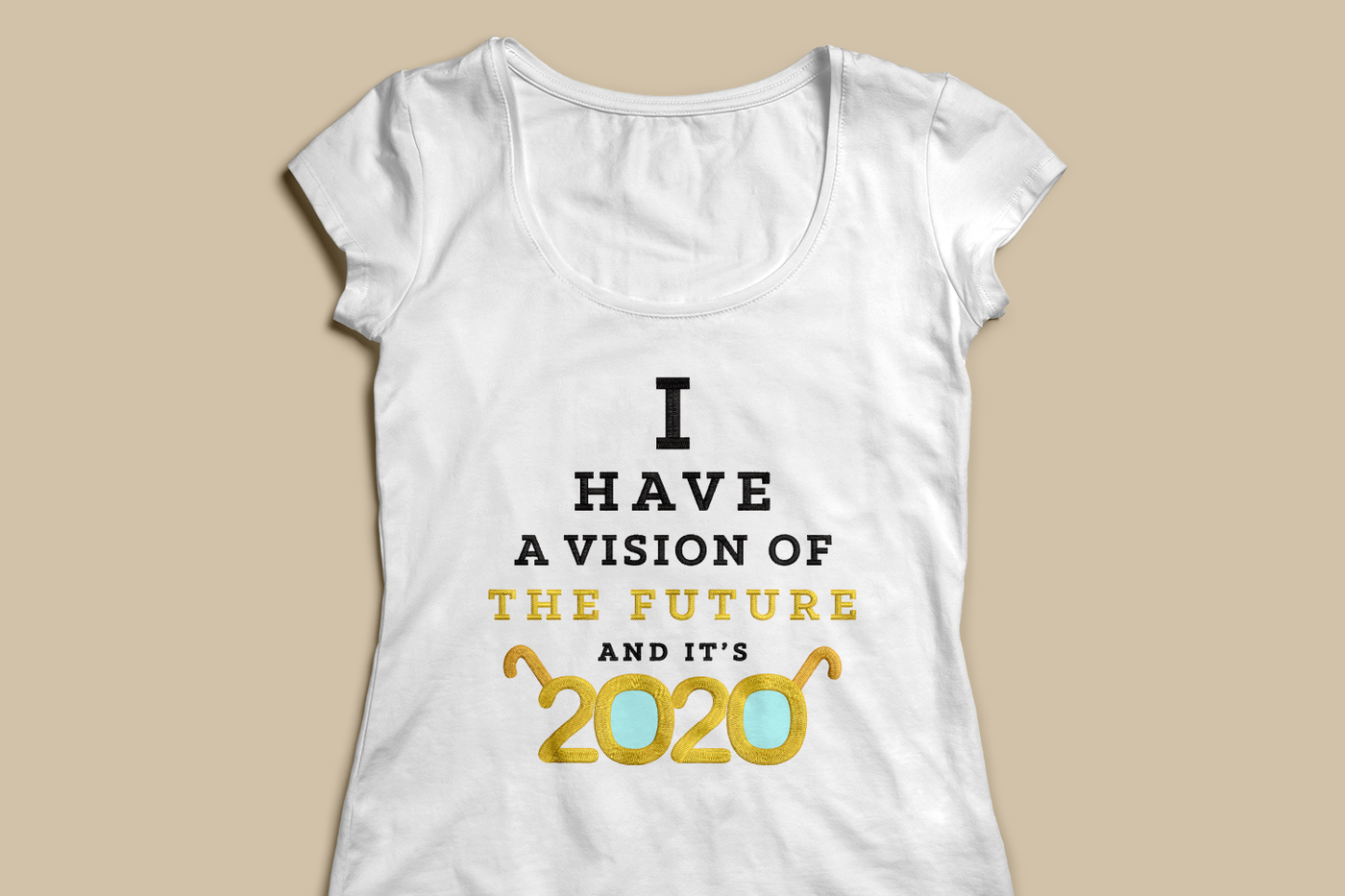 A white scoopneck tee sits on a beige background. There is an embroidered design that says "I have a vision of the future and it's 2020. The letters look like an eye chart and the 2020 has arms to look like glasses.