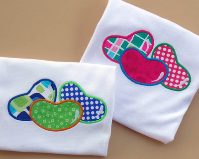 Two folded tees, each featuring an applique design of 3 large jelly beans.