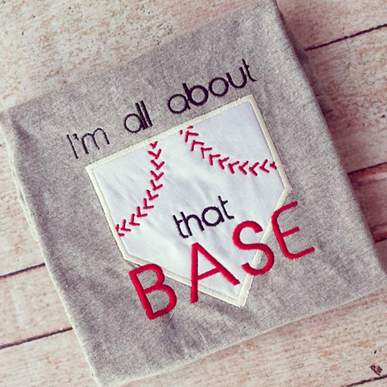 Applique of a home plate with red baseball style stitching and the embroidered words "I'm all about that base."