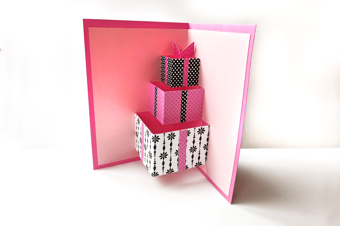 Inside of a greeting card with pop up gift boxes in pink, black, and white wrap.