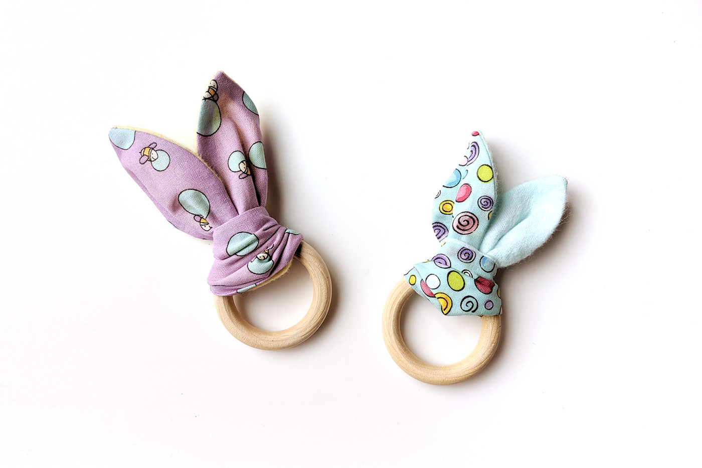 Two wooden rings, each with fabric on them to make a bunny ear style teether.