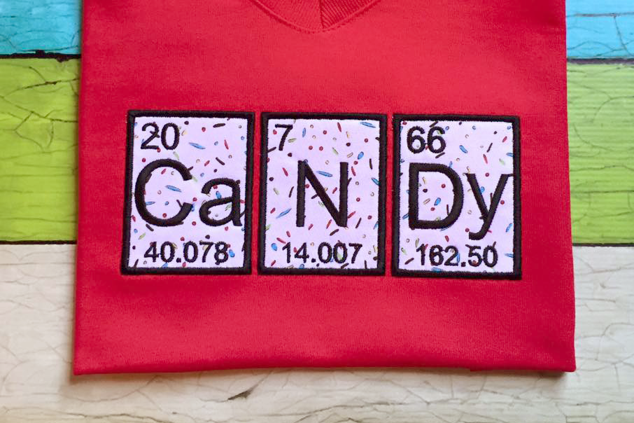Candy applique on pink shirt, spelled out of 3 periodic elements.
