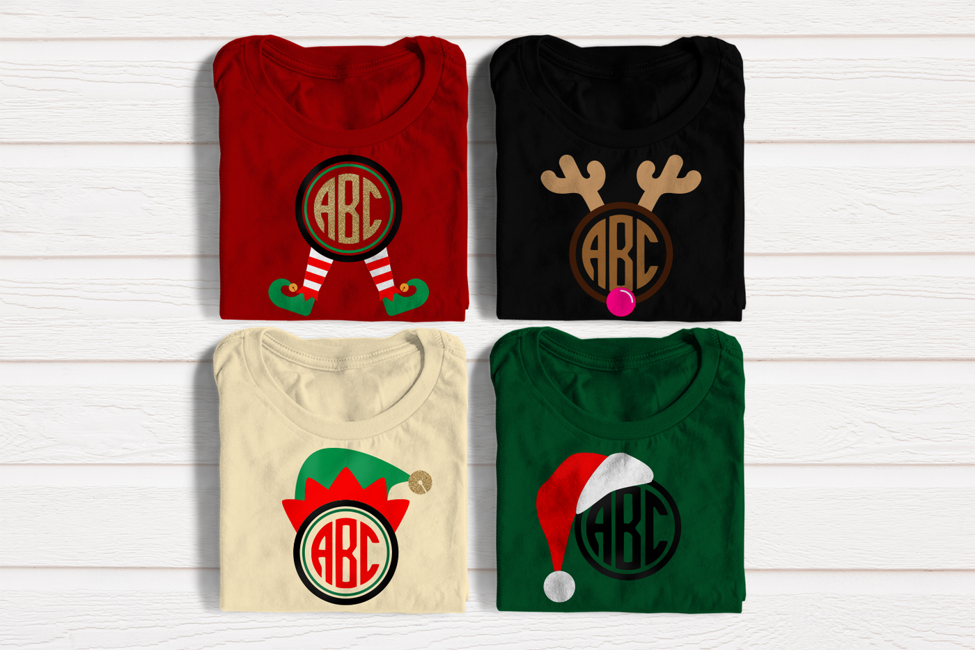 Four folded tees in Christmas colors. Each has a round monogram frame with sample monogram letters (not included). The included frame designs are elf legs, an elf hat, reindeer horns and nose, and a Santa hat.