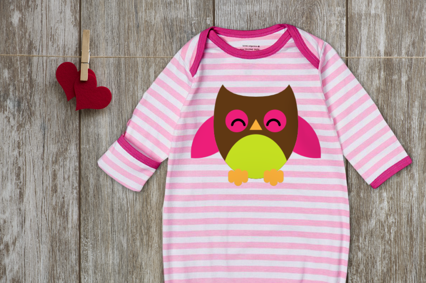 A pink and white striped baby sleep sac decorated with a cute smiling owl.