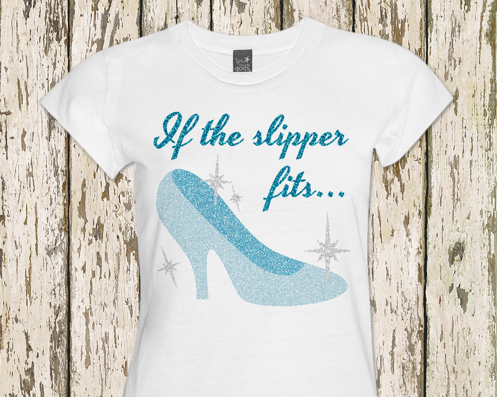 A white shirt has a pale blue slipper in glitter vinyl with sparkles all around it. Above in blue glitter it says "If the slipper fits..."