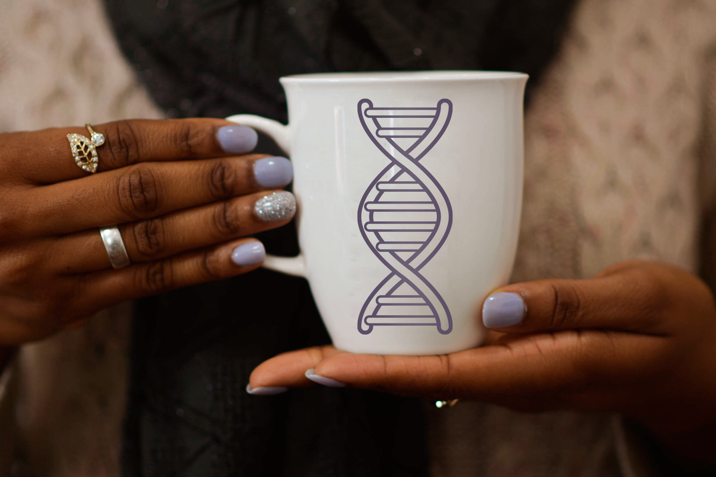 DNA design on a mug being held by a black woman with lavender nails.