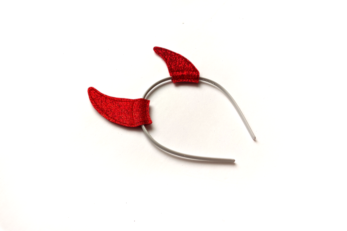 Red glitter devil horn headband on a white background.