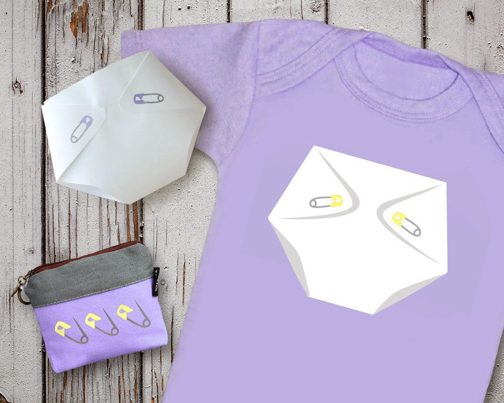 A lavender onesie with a cloth diaper design with yellow pins. Next to it is a lavender small zipper bag with a design of 3 yellow diaper pins. There is also a paper design folded to look like a cloth diaper with lavender diaper pins on it.