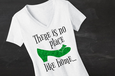 White tee with a green show that says "There is no place like home..."