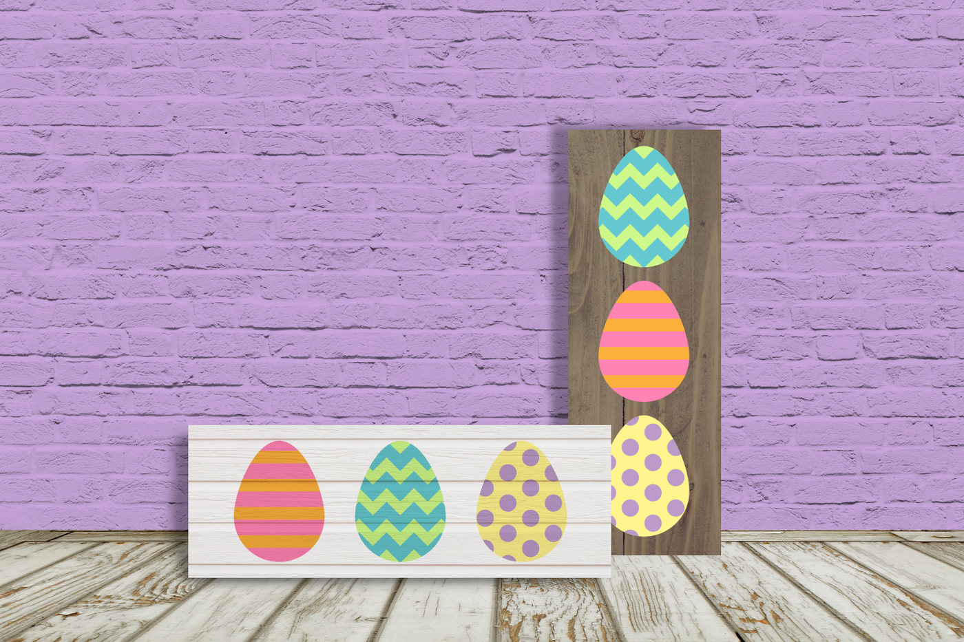 Two porch signs lay against a wall. One is vertical, the other is horizontal. Each is decorated with 3 Easter eggs. One egg has a chevron pattern, one has a striped pattern, and one has polka dots.