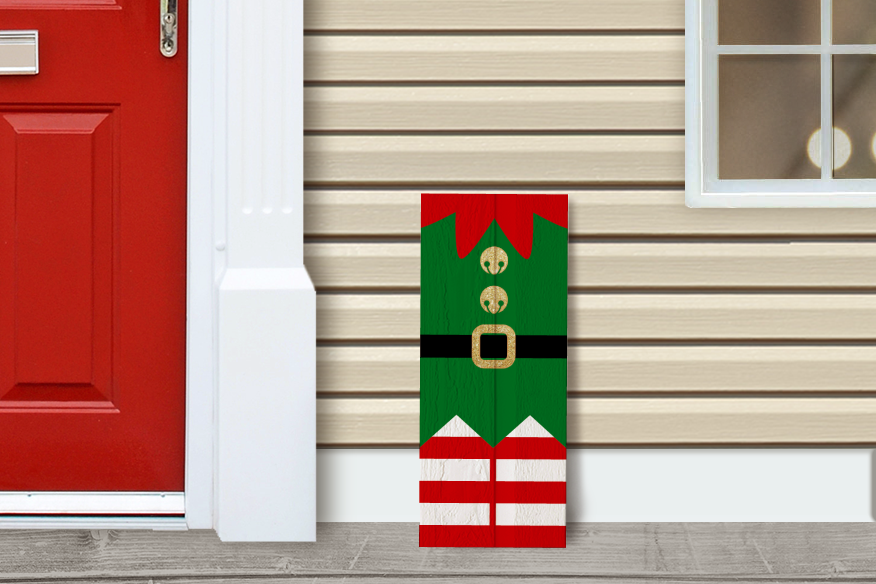 A front porch with a red door. A vertical sign decorated like an elf's outfit sits in front.