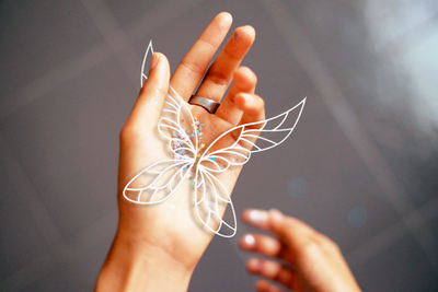 A hand holding glitter and a pair of detailed fairy wings
