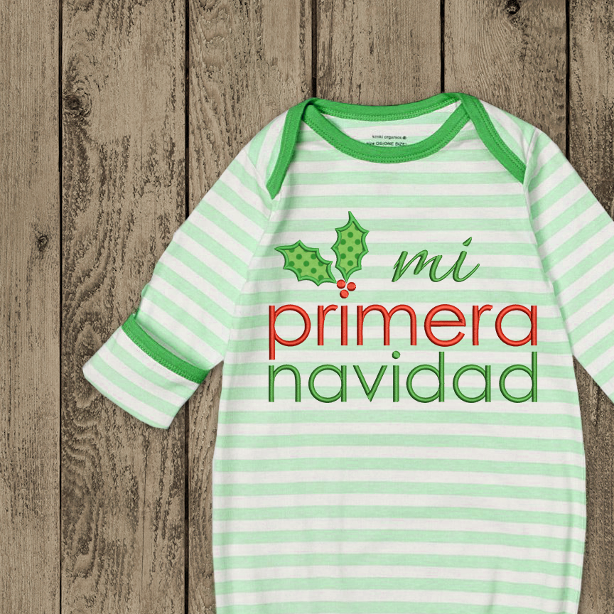 Baby sleep gown with an embroidery design that says "mi primera navidad" and holly leaves and berries dotting the i