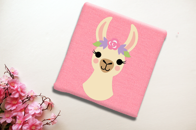 Folded tee with a llama from the neck up, wearing a flower crown.