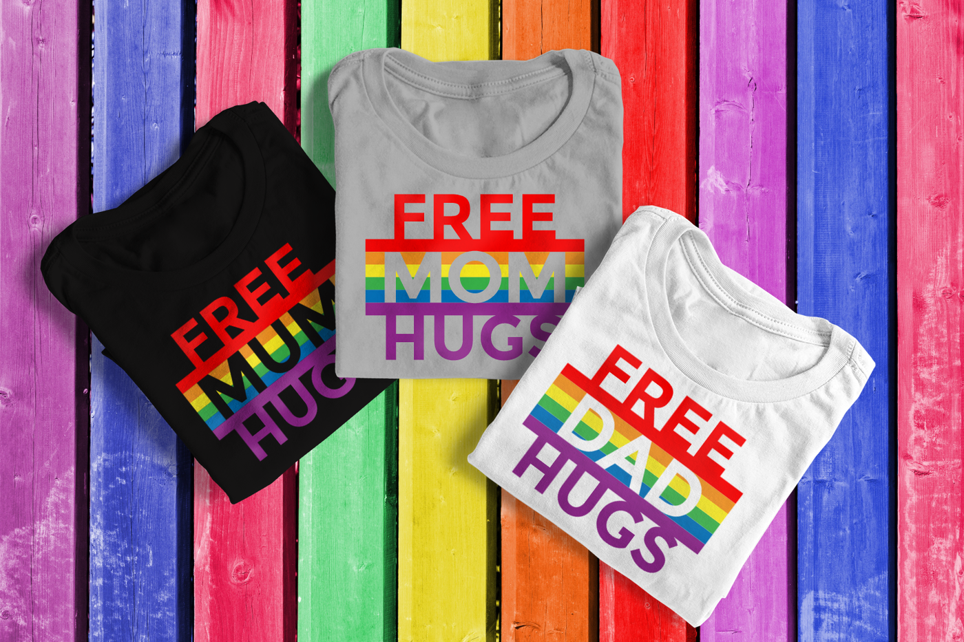 Three folded tees. Each has rainbow stripes and the phrase "free hugs." Mum, Mom, and Dad are knocked out of each of the rainbow areas.