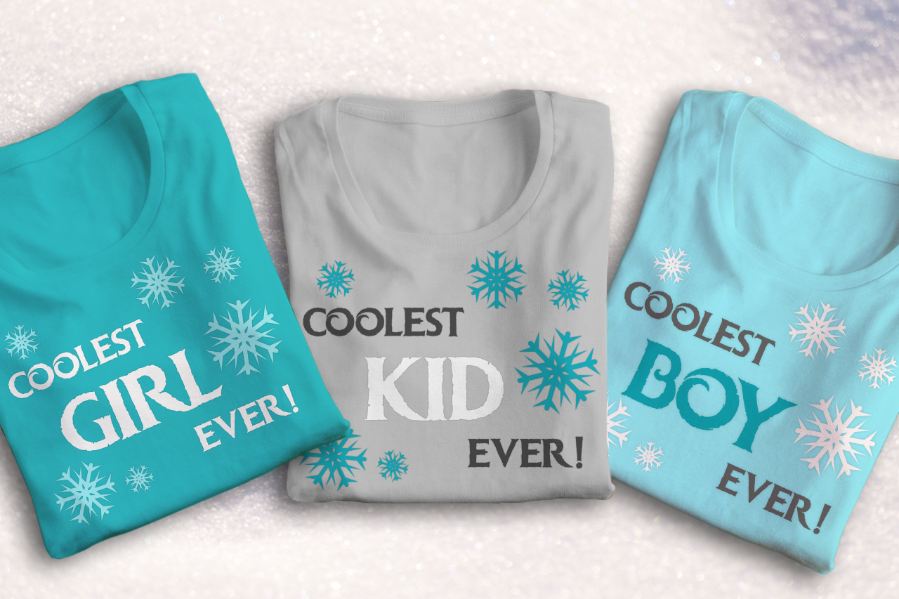 Three folded tees laying on snow. Each has snowflakes on them. One says "Coolest girl ever," one says "Coolest kid ever," and the third says "coolest boy ever."