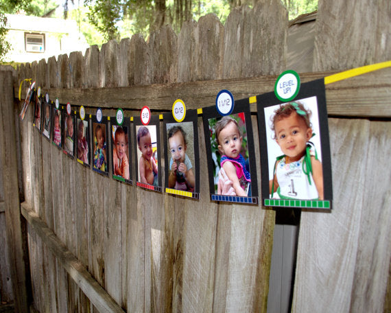 A photo banner hanging on a fence. Each has an photo of a black baby girl at a different age. Below is a life meter. Above is a circle indicating the number of months out of 12. For the last, it says "Level up!"