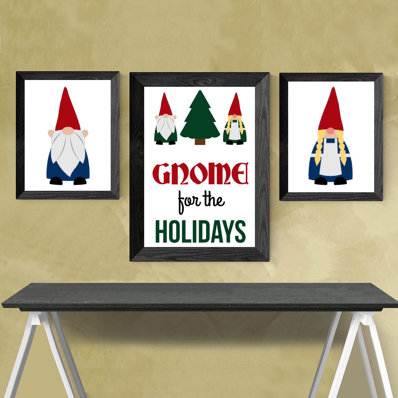 Three framed posters over a table. The middle has two gnomes with a tree and says "Gnome for the holidays." One gnome has braids, the other has a beard. At the left and right are larger versions of the boy and girl gnomes.
