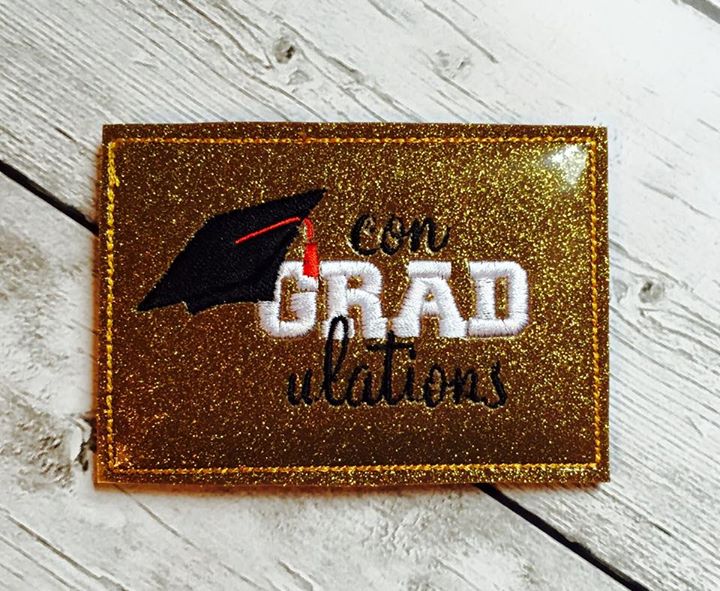Gift card holder made out of gold vinyl. It says "con-GRAD-ulations" with a grad cap hanging from the G.