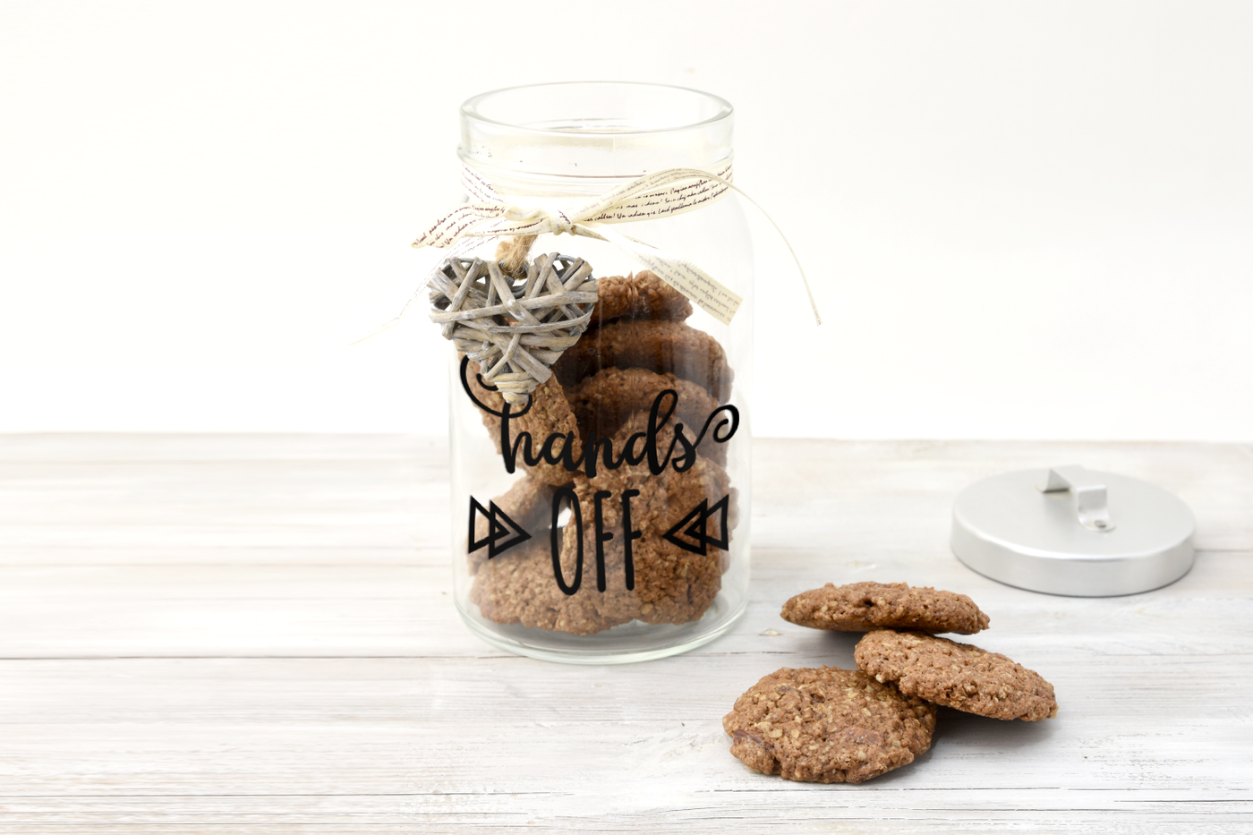 Cookie jar filled with cookies. On the jar, it says  "hands OFF" with decorative triangles on either side.