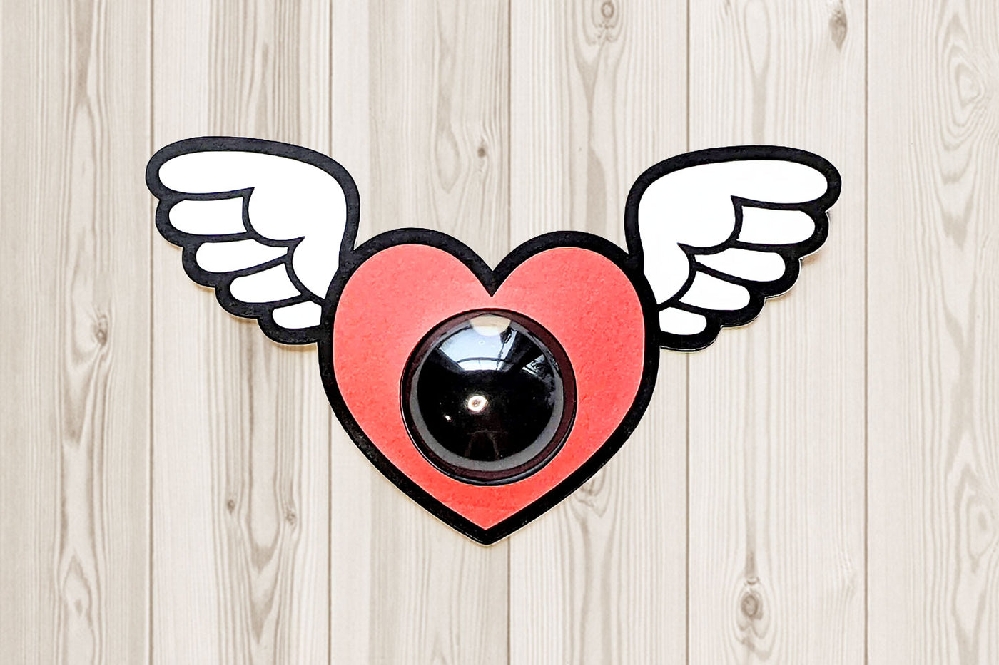 Heart with wings holding a candy dome SVG