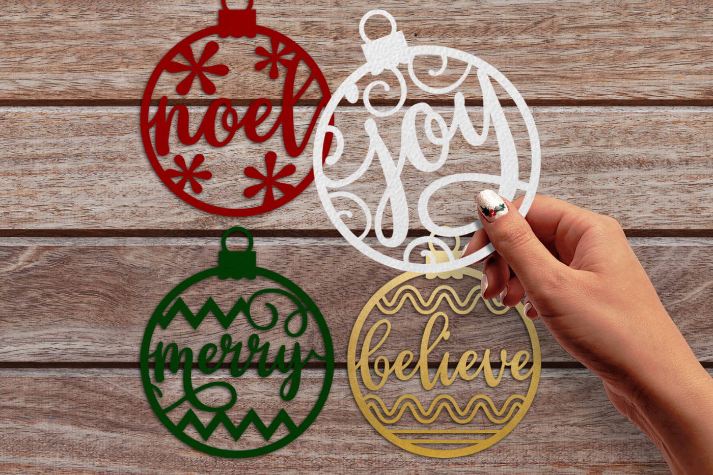 Papercut Christmas ornaments with the words "joy," "noel," "merry," and "believe."