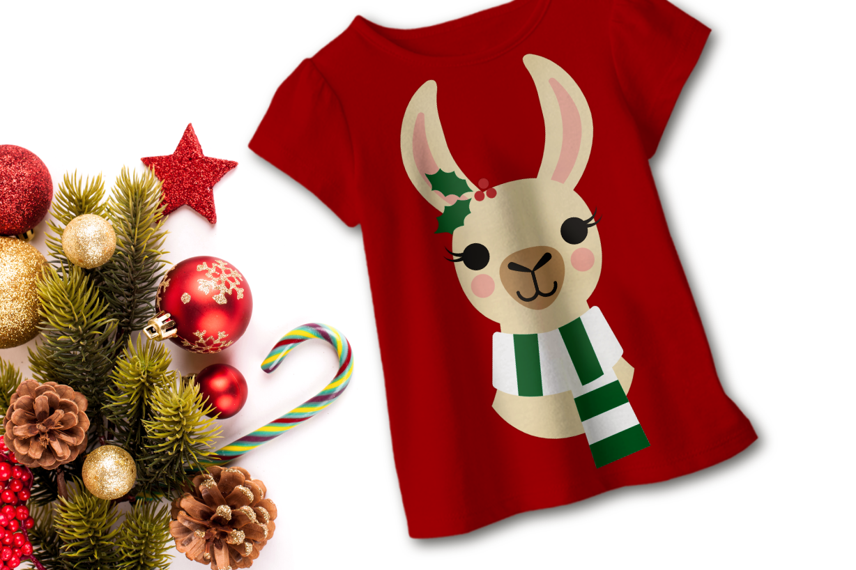 A red child's shirt on a white background. Near it are Christmas decorations, sprigs of evergreen, and a candy cane. On the shirt is a llama wearing a striped scarf with holly on one ear. Shown from the neck up.