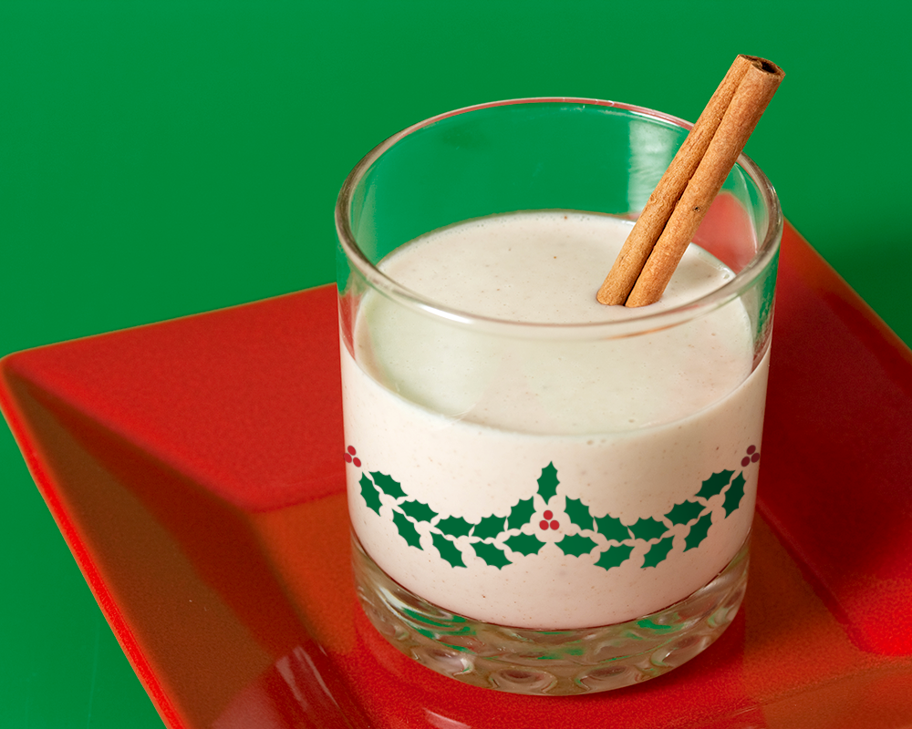 Glass of egg nog with a holly garland design.