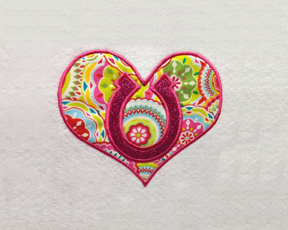 Applique design of a heart with a horseshoe inside.