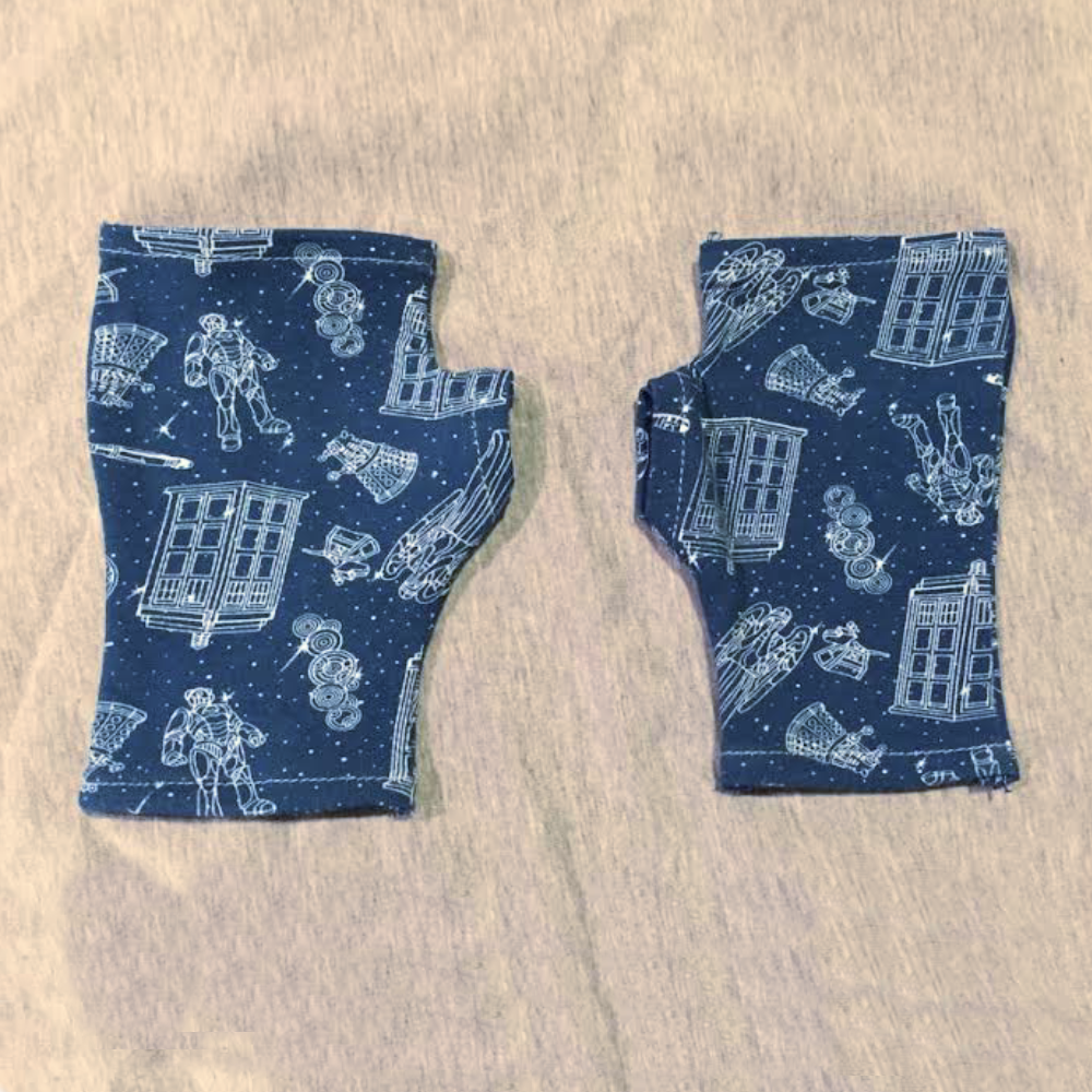 A pair of fingerless gloves made out of blue and white Doctor Who fabric.