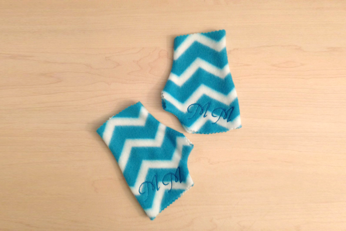 A pair of fingerless gloves in blue and white chevron fleece. Monograms have been added.