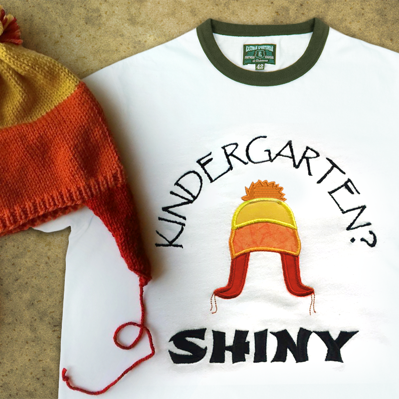 Ringer tee with an applique winter hat and embroidered words that say "Kindergarten? Shiny."