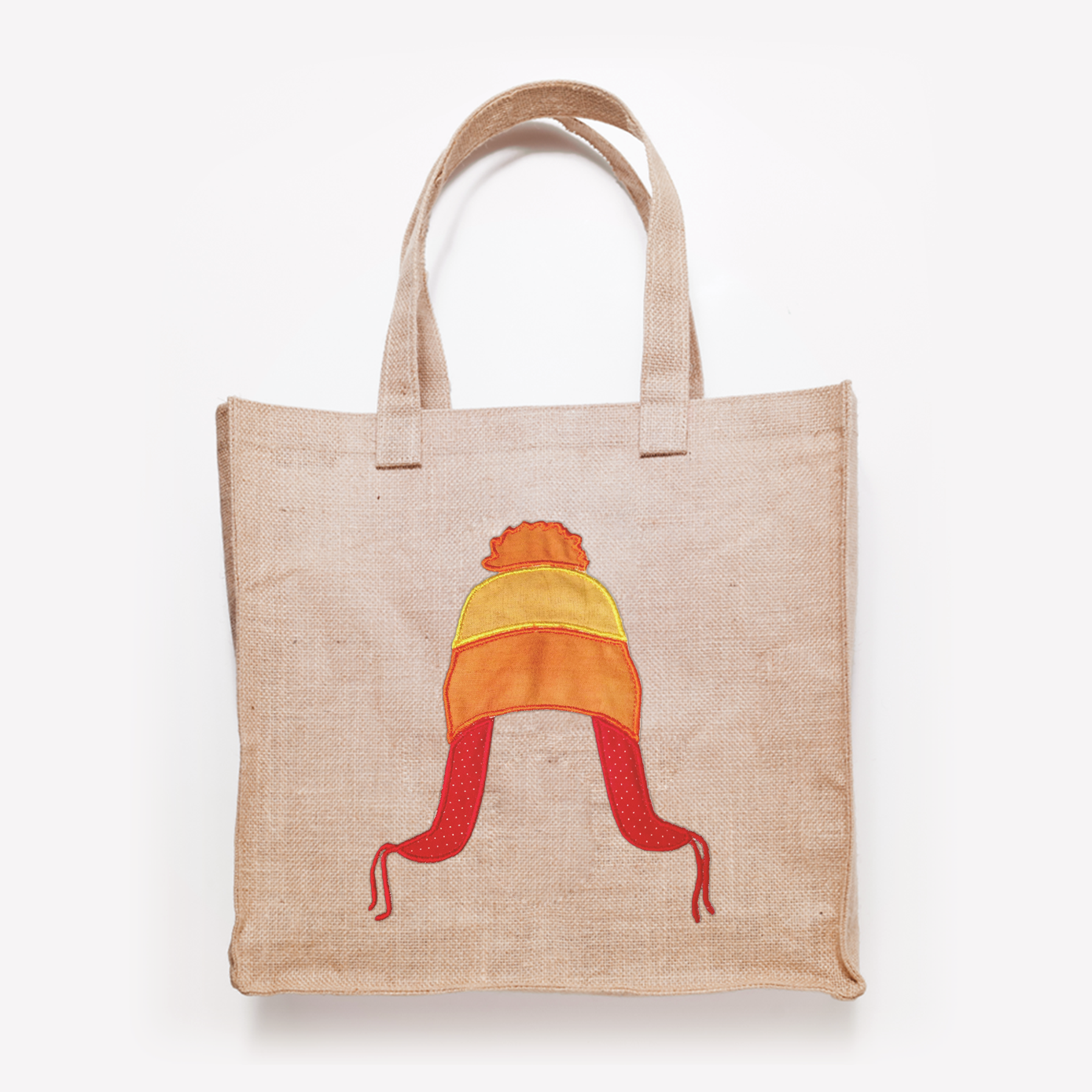 Tote bag with an applique design of a tri-colored winter hat with flaps and a pom pom