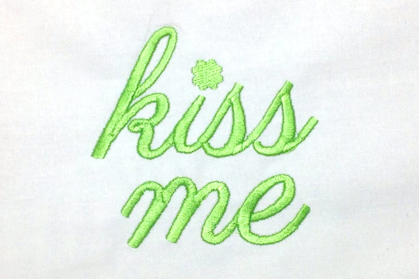 Embroidery design that says "kiss me" with a clover for the dot on the i.