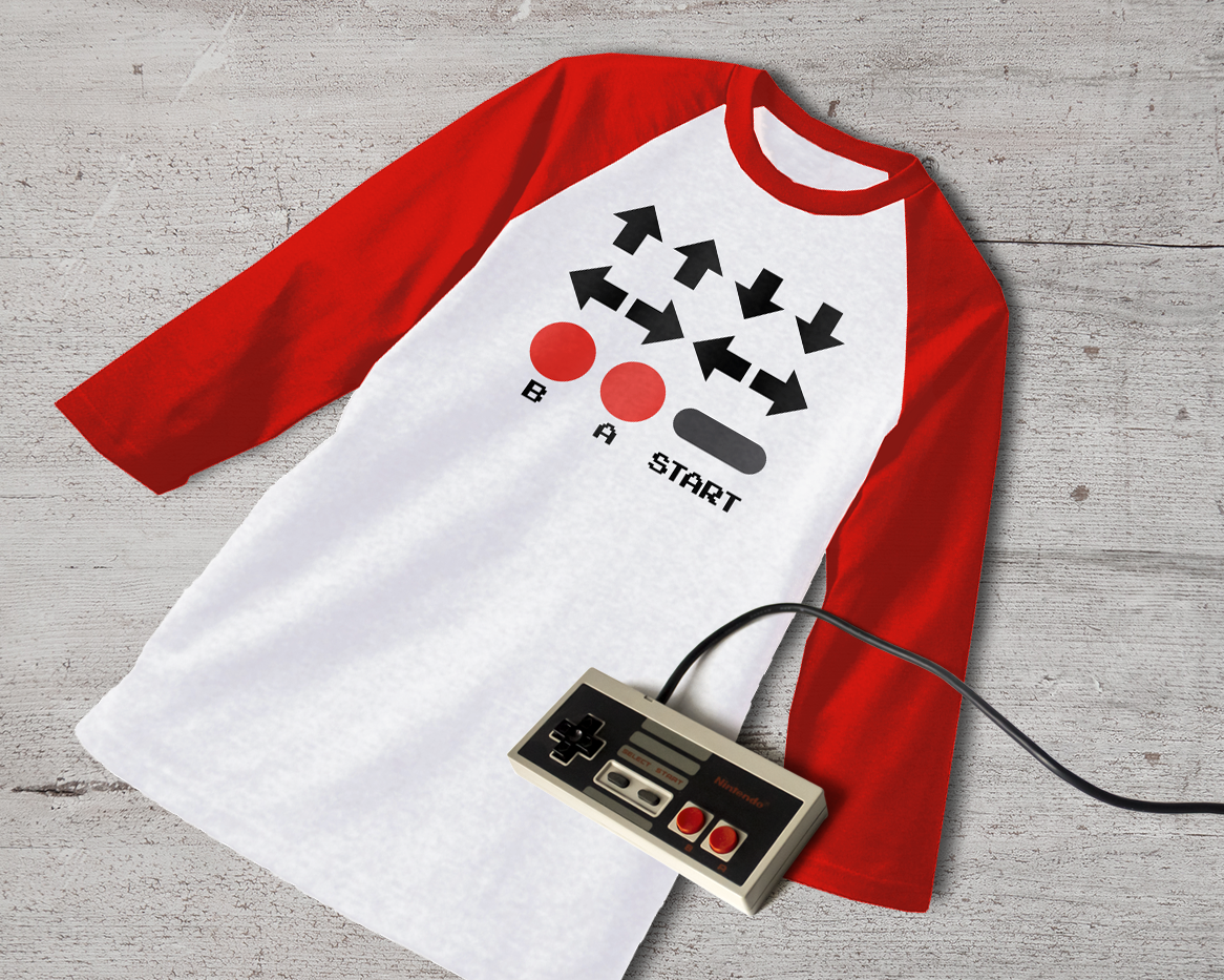 Raglan tee with 2 up arrows, 2 down arrows, two pairs of left and right arrows, a red B button, a red A button, and a start button.
