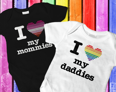 Two baby onesies. One says "I heart my mommies" and the other says "I heart my daddies." The hearts are made out of stripes in pride flag colors.