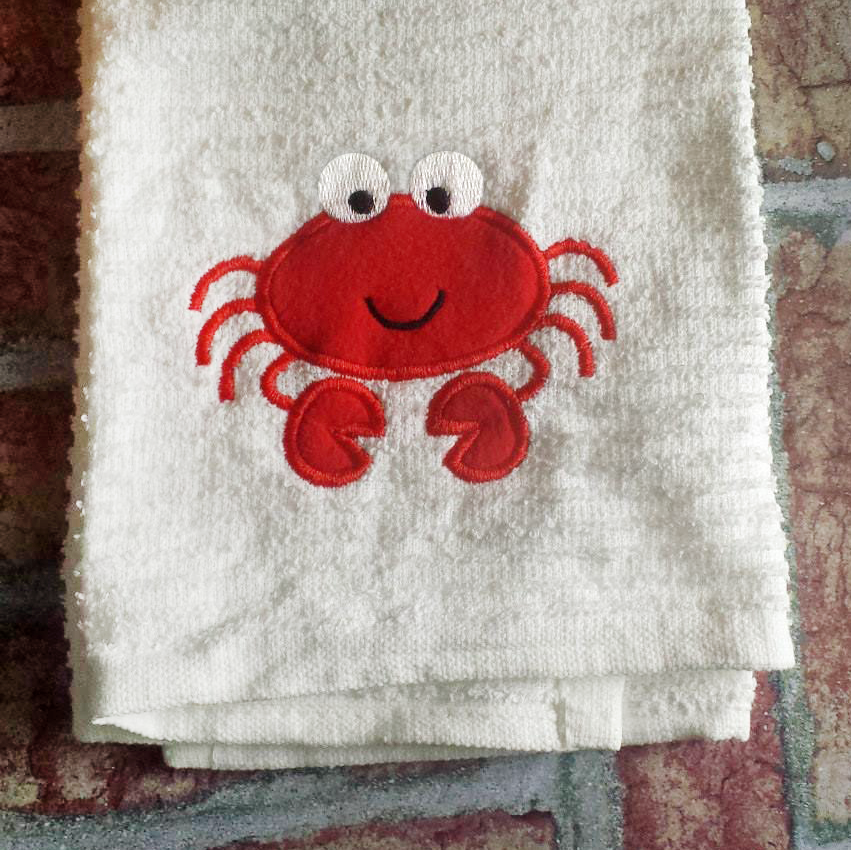 A cute cartoon crab appliqued onto a white towel.