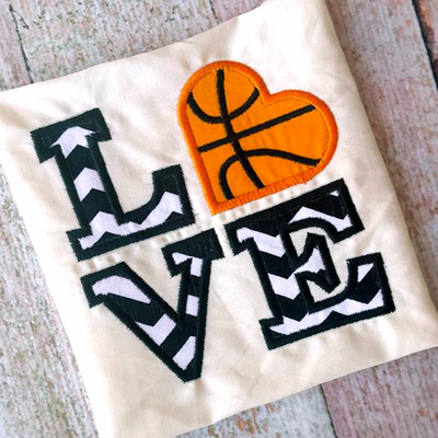 LOVE applique set on a square. A heart is in place of the O and has lines added to look like a basketball.