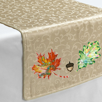 A golden table runner with appliques of an acorn and two leaves.
