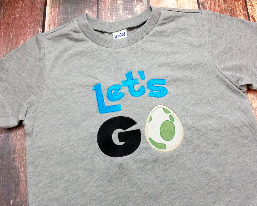 Applique of the phrase "Let's GO" with a spotted egg in place of the O.