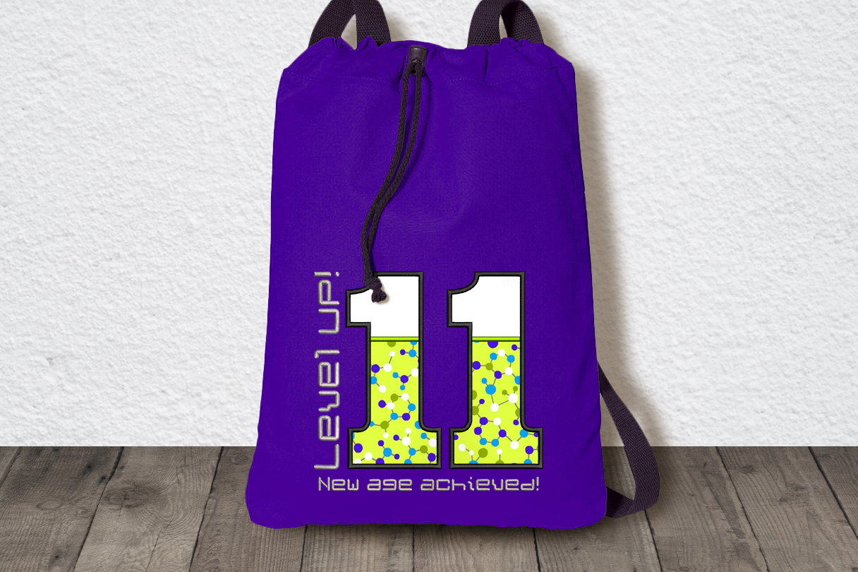 Bag with large 11 applique. Around the number is the embroidered text "Level UP! New age achieved!"
